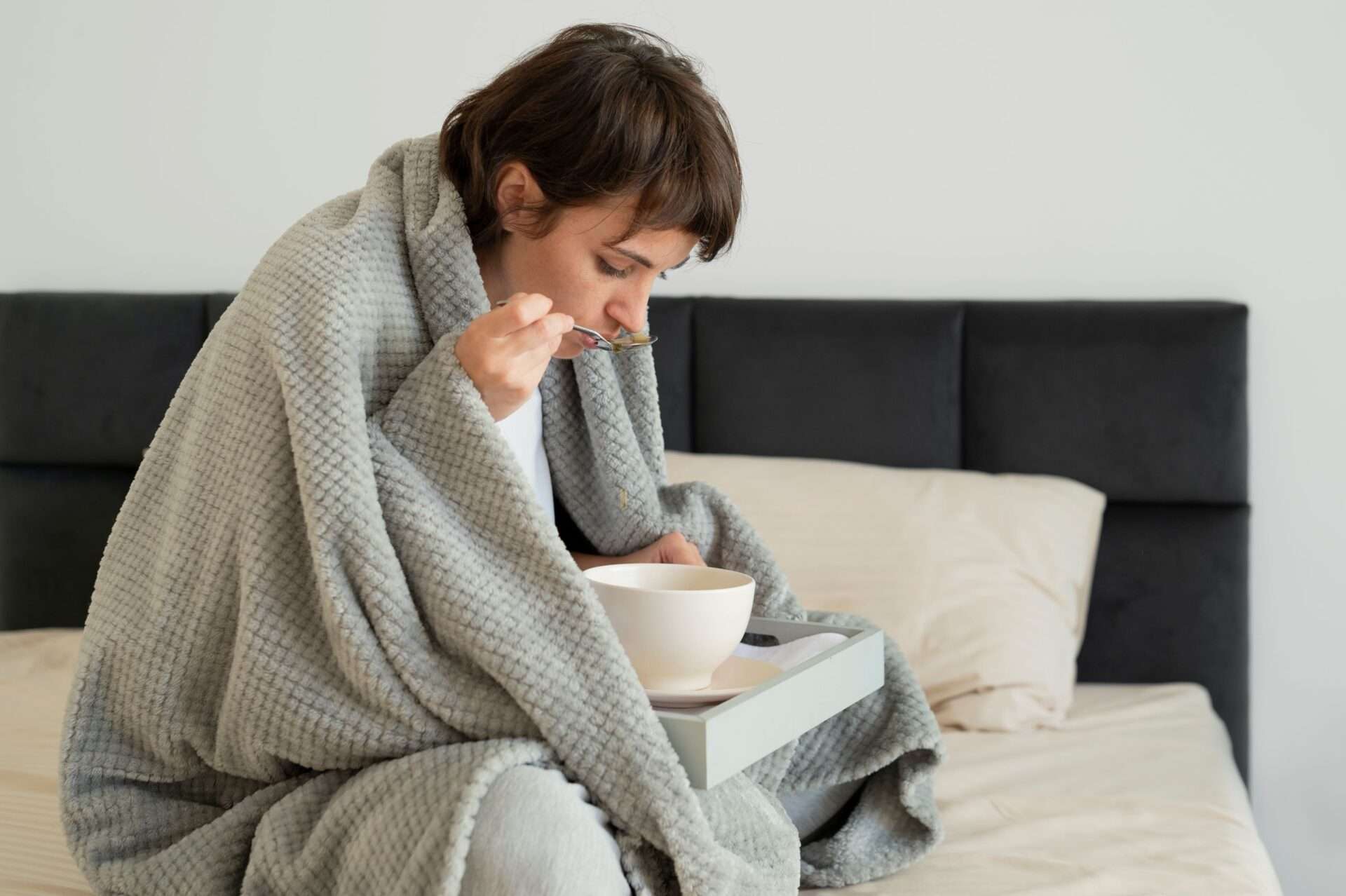 woman at home sick eating soup