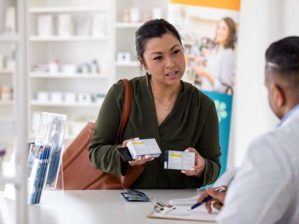 woman at pharmacy counter holding medicines